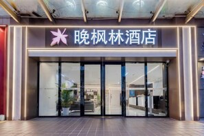 A hotel entrance with a modern design, featuring a large glass door and a sign above.