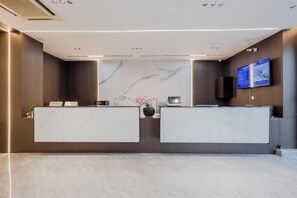 A reception area with marble countertops, a digital screen, and a wall-mounted speaker. - Wanfenglin Hotel (Shanghai Heqing Meijiayi Plaza Branch) (Shanghai)