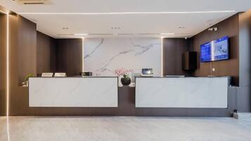 A reception area with marble reception desks, a digital display, and a wall-mounted screen.