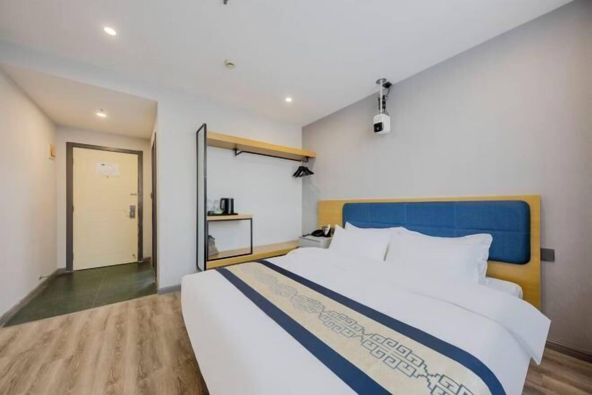 Una habitación de hotel con cama, escritorio, silla, espejo y puerta.