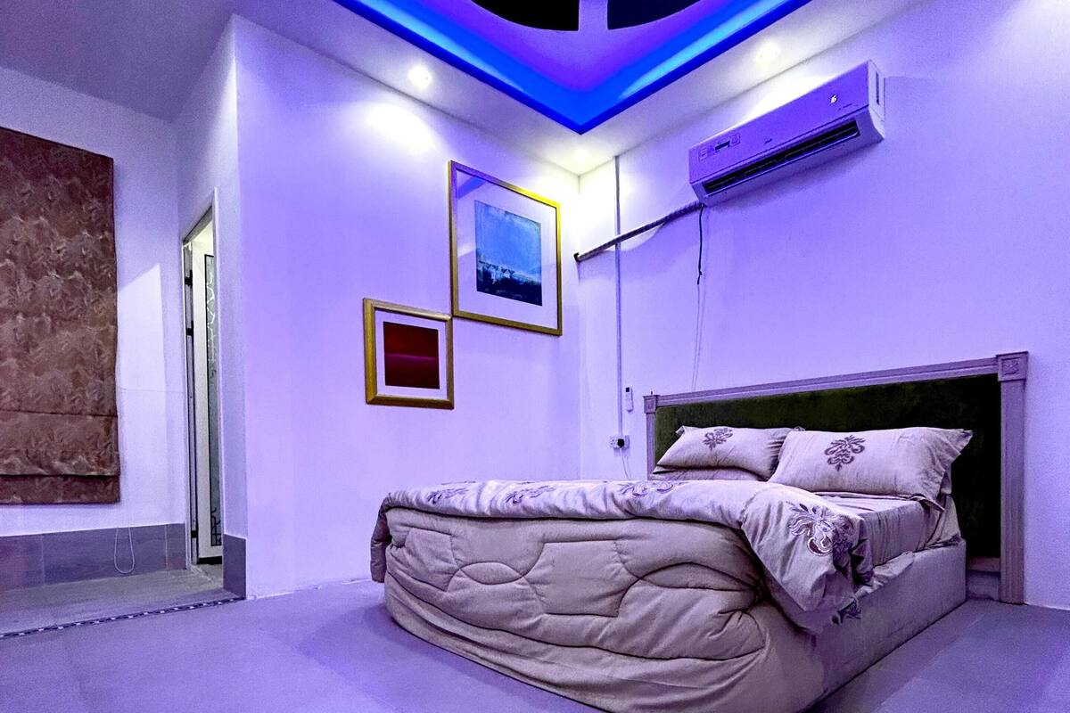 Ein Schlafzimmer mit einem Bett, einer Deckenleuchte und einer wandmontierten Klimaanlage.