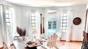 Un vaste espace dédié à la salle à manger, avec une grande table en bois, des chaises blanches et un buffet bleu.