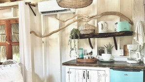 A rustic kitchen with a wooden ceiling, a hanging wicker light fixture, a white cabinet with a blue refrigerator, and a wooden bench. - Shipwreck Cove (Caye Caulker)
