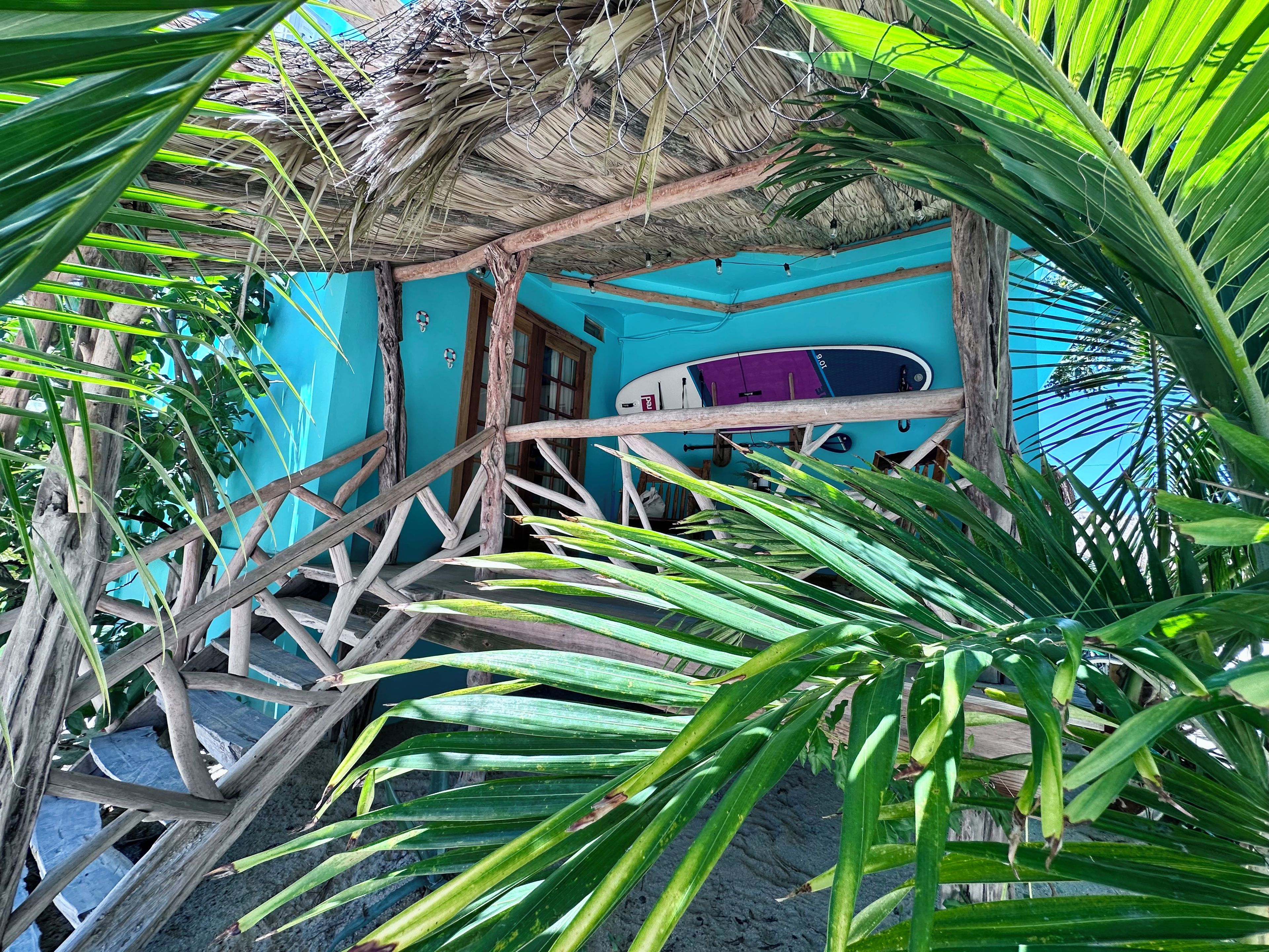 Ein Zimmer mit einem Strohdach, einem Surfbrett und einer blauen Wand.