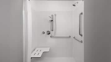 Un espace douche moderne équipé d’une barre d’appui, d’un pommeau de douche et d’un flexible de douche.