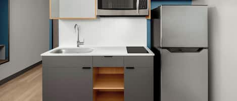 A modern kitchen with a built-in microwave, a refrigerator, and a sink.