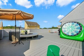 A rooftop deck with a dartboard, outdoor seating, and a large umbrella.