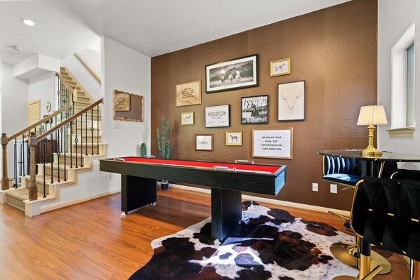 A room with a pool table, a cactus, and a staircase.