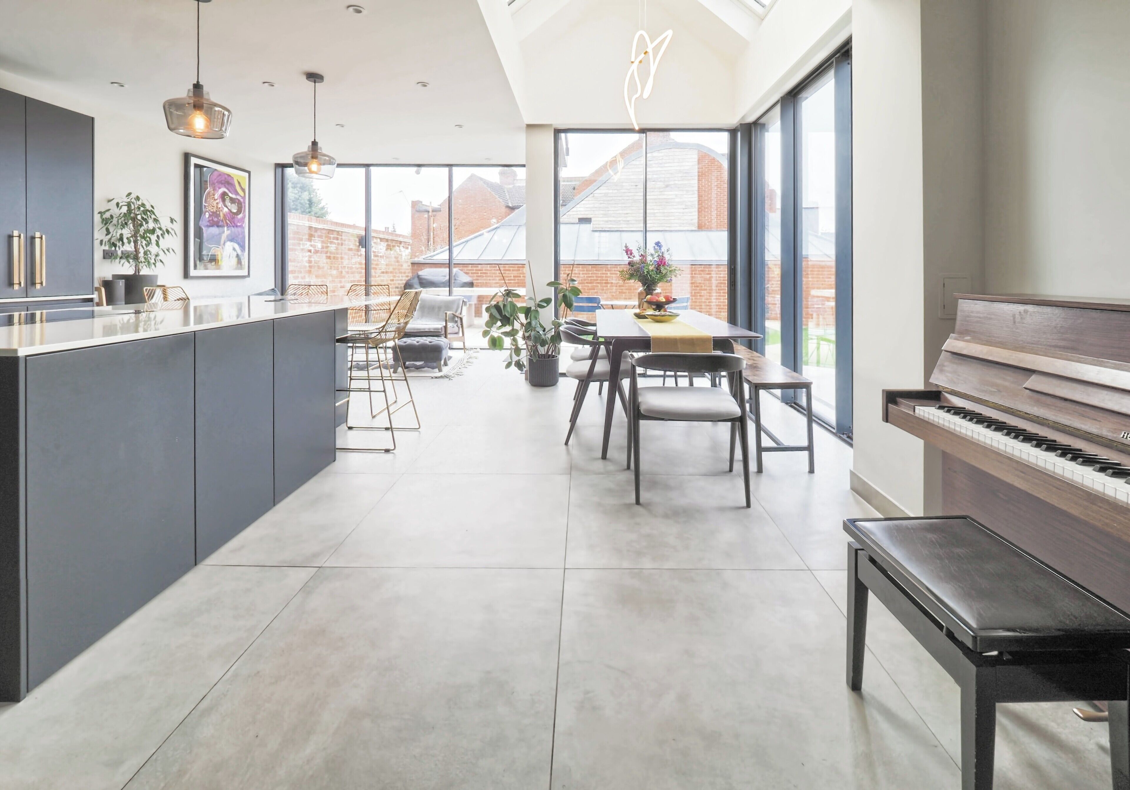 Una cocina moderna con una isla central, zona de comedor y un piano.
