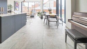 Una cocina moderna con una isla central, zona de comedor y un piano.