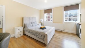 Una camera da letto con un letto, un comodino, una lampada e una finestra vista edifici.