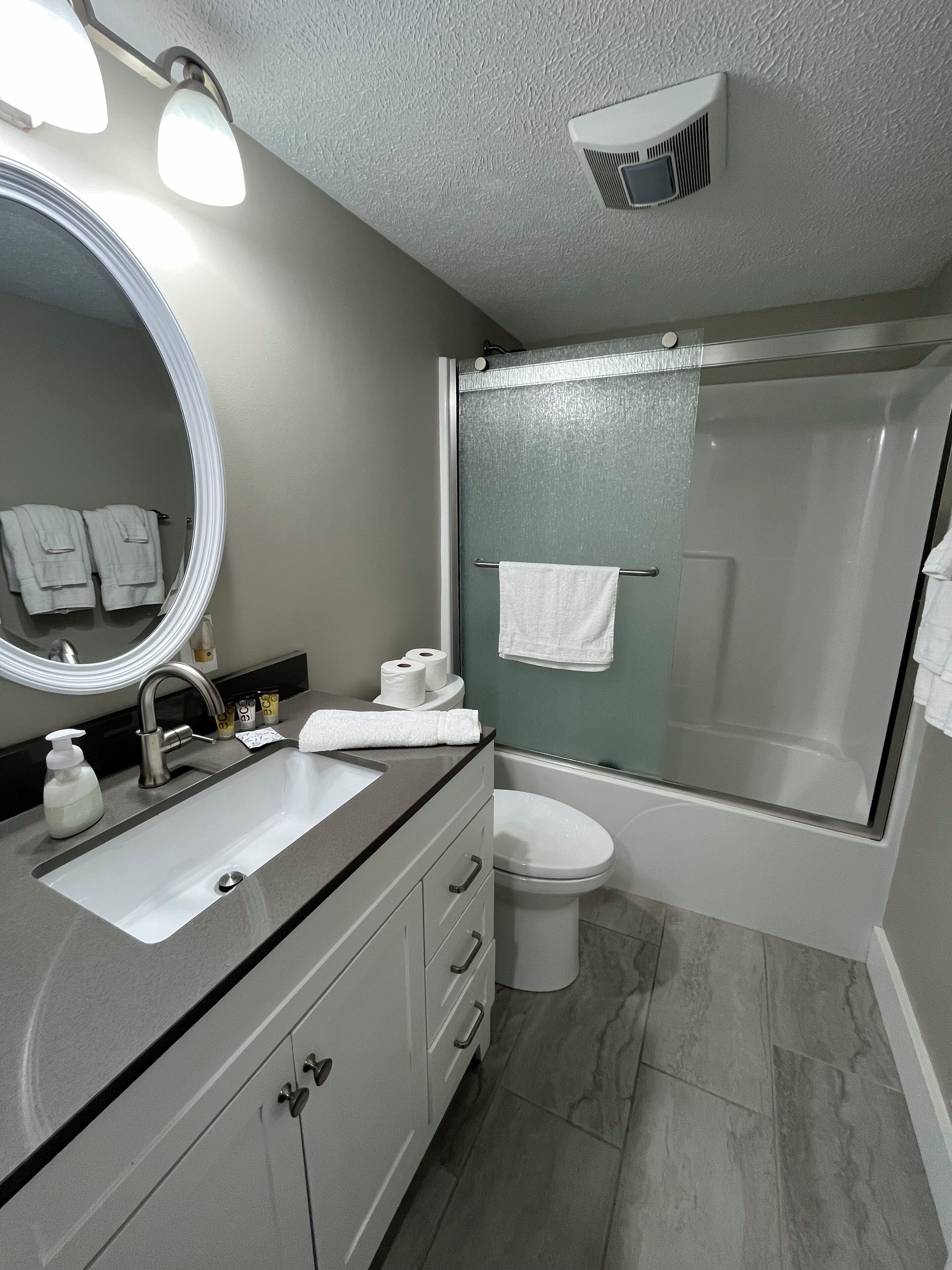 A modern bathroom with a sink, mirror, and shower.