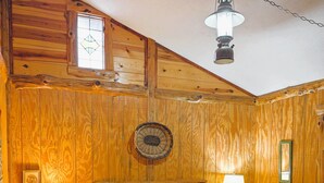 A wooden-paneled bedroom with a bed, two bedside lamps, and a hanging light fixture. - Once a Blacksmith shop, now a 3-bedroom cabin beauty in the heart of the Ozarks (Yellville)