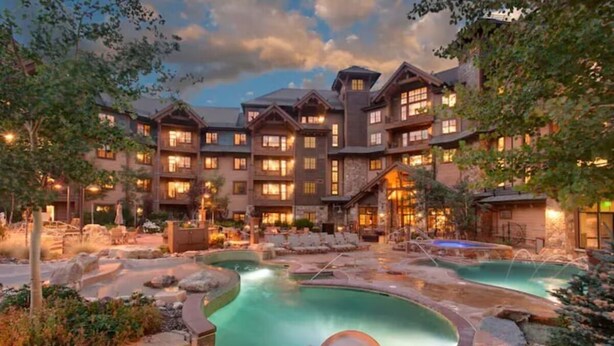 Ein Resort mit Poolbereich, mehreren Gästezimmern und einer Steinfassade.