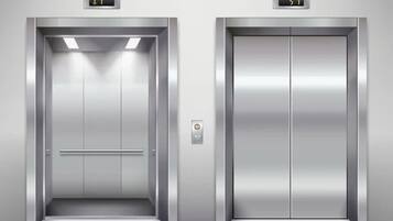 Two elevator doors with digital displays indicating floor numbers.