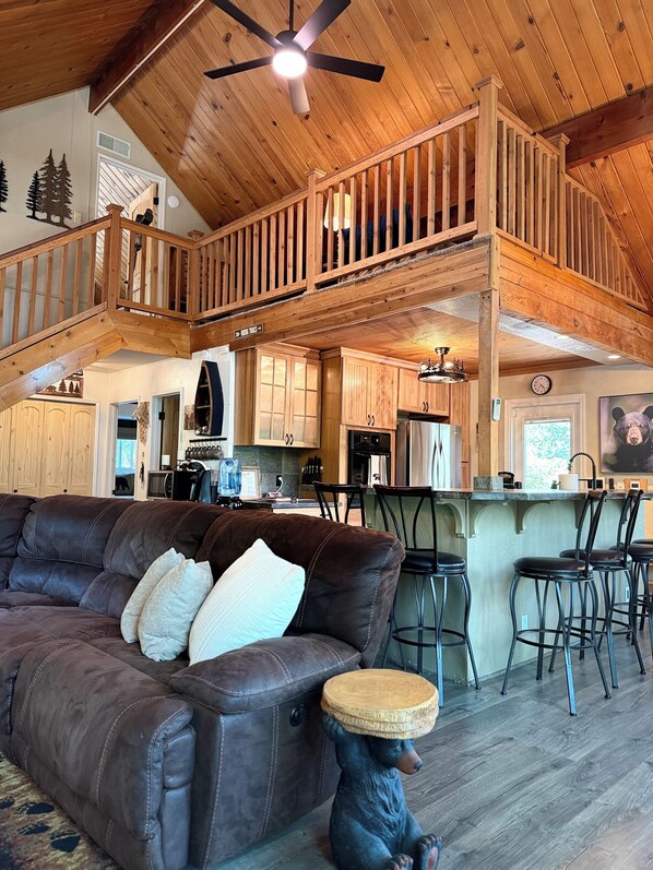 Ein geräumiger Wohnbereich mit Ledersofa, Holzboden und einer Bärenstatue.