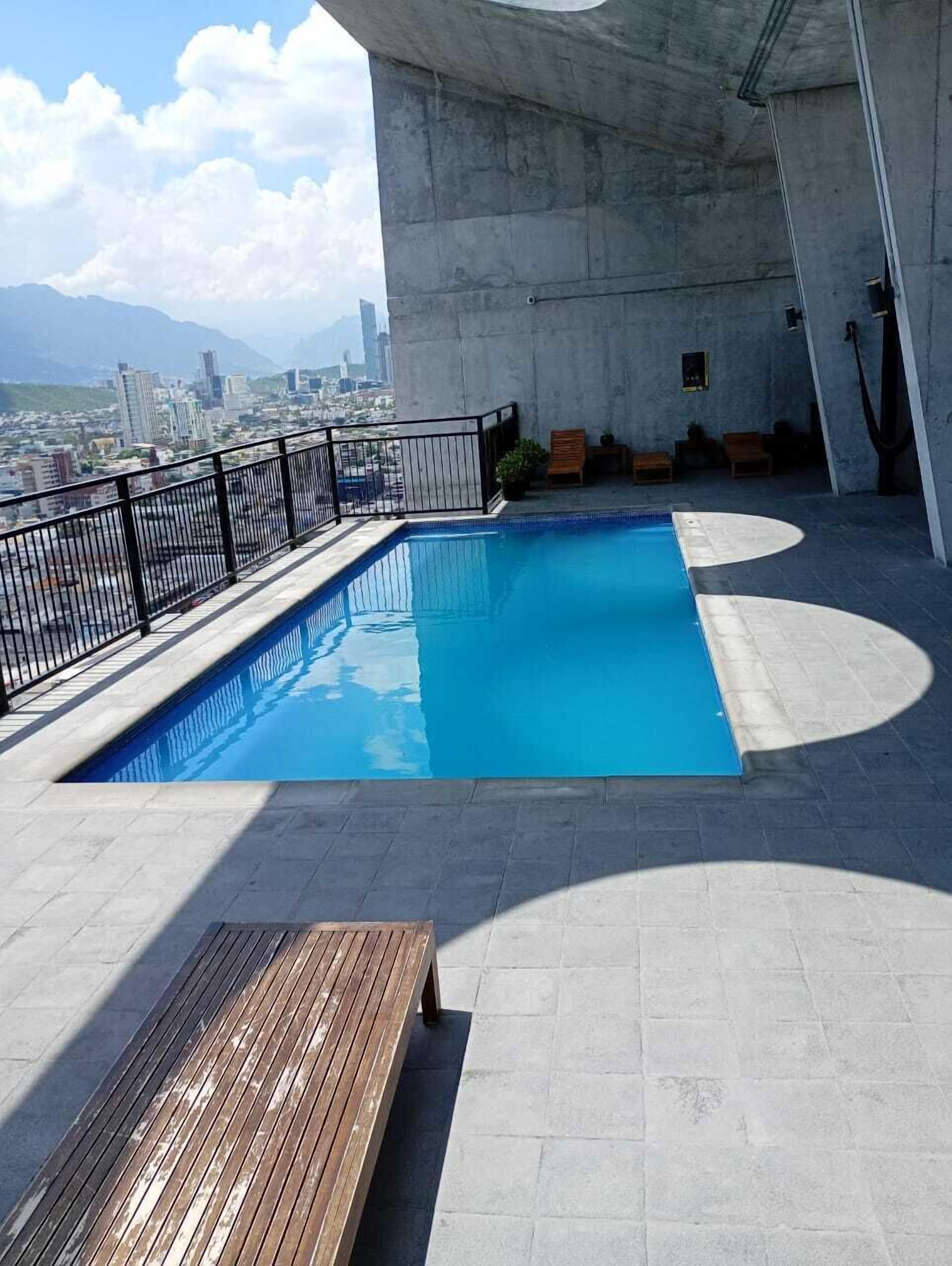 A rooftop pool with a view of a cityscape and mountains.