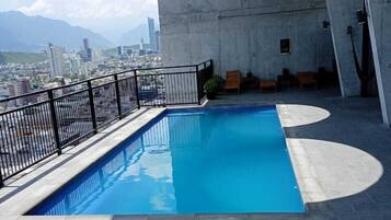 A rooftop pool with a view of a cityscape and mountains.