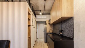 Una cucina stretta con mobili in legno, un piano di lavoro nero e una parete rivestita di piastrelle.