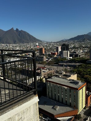 Paisagem urbana com uma montanha imponente ao fundo, mistura de edifícios modernos e antigos, e céu claro.