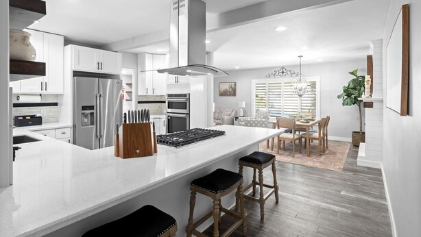 A modern kitchen with white cabinetry, a central island with stools, and a dining area with a chandelier. - Family Paradise-Kid and Pet Friendly Home by Encanto Golf Course-Downtown  Phx. (Phoenix)