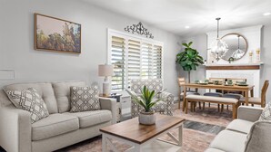 A living room with a sofa, coffee table, and dining area with chairs and a table. - Family Paradise-Kid and Pet Friendly Home by Encanto Golf Course-Downtown  Phx. (Phoenix)