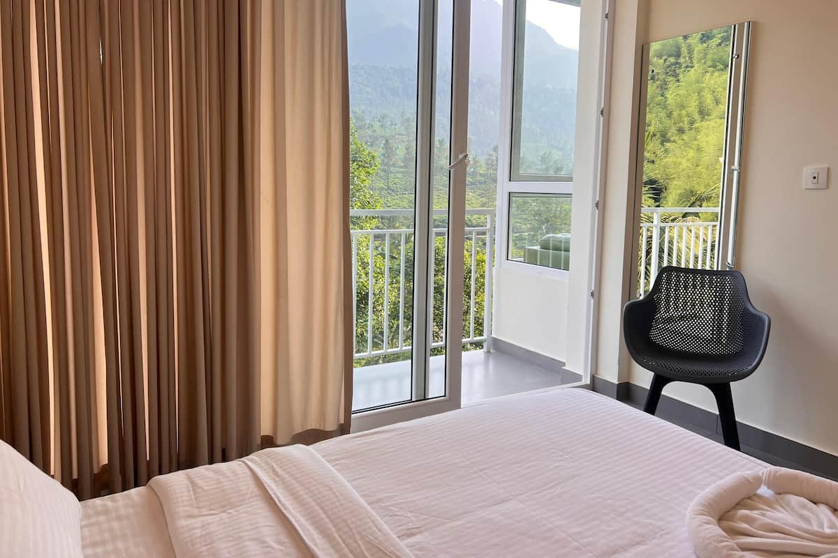 A hotel room with a bed, a chair, and a balcony with a mountain view.