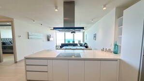 A modern kitchen with a central island, built-in cabinets, and a large window overlooking the ocean. - Barcelona 307 Ocean Front Brand New 3-bedroom condo. WiFi in lovely Las Palomas (Puerto Peñasco)