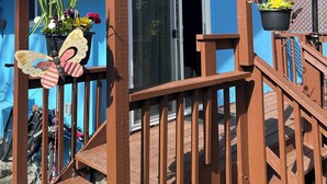 A blue building with a wooden deck, a 'WELCOME' sign, and hanging flower baskets. - The best room to relax (Nanoose Bay)