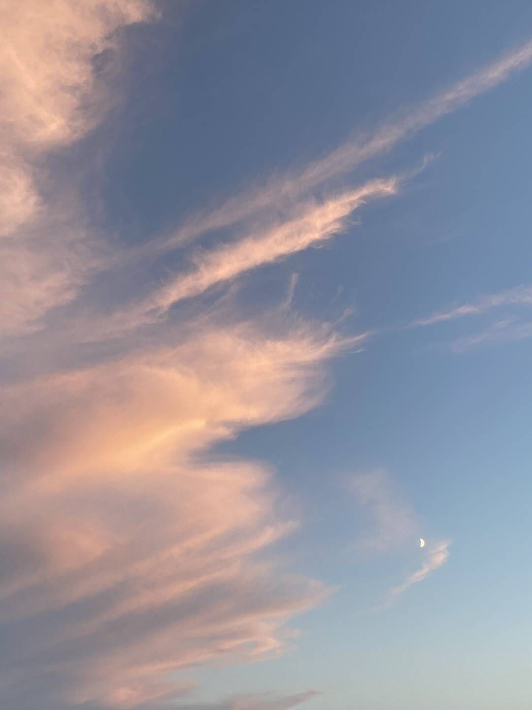 Klar himmel med lette skyer og en halvmåne.
