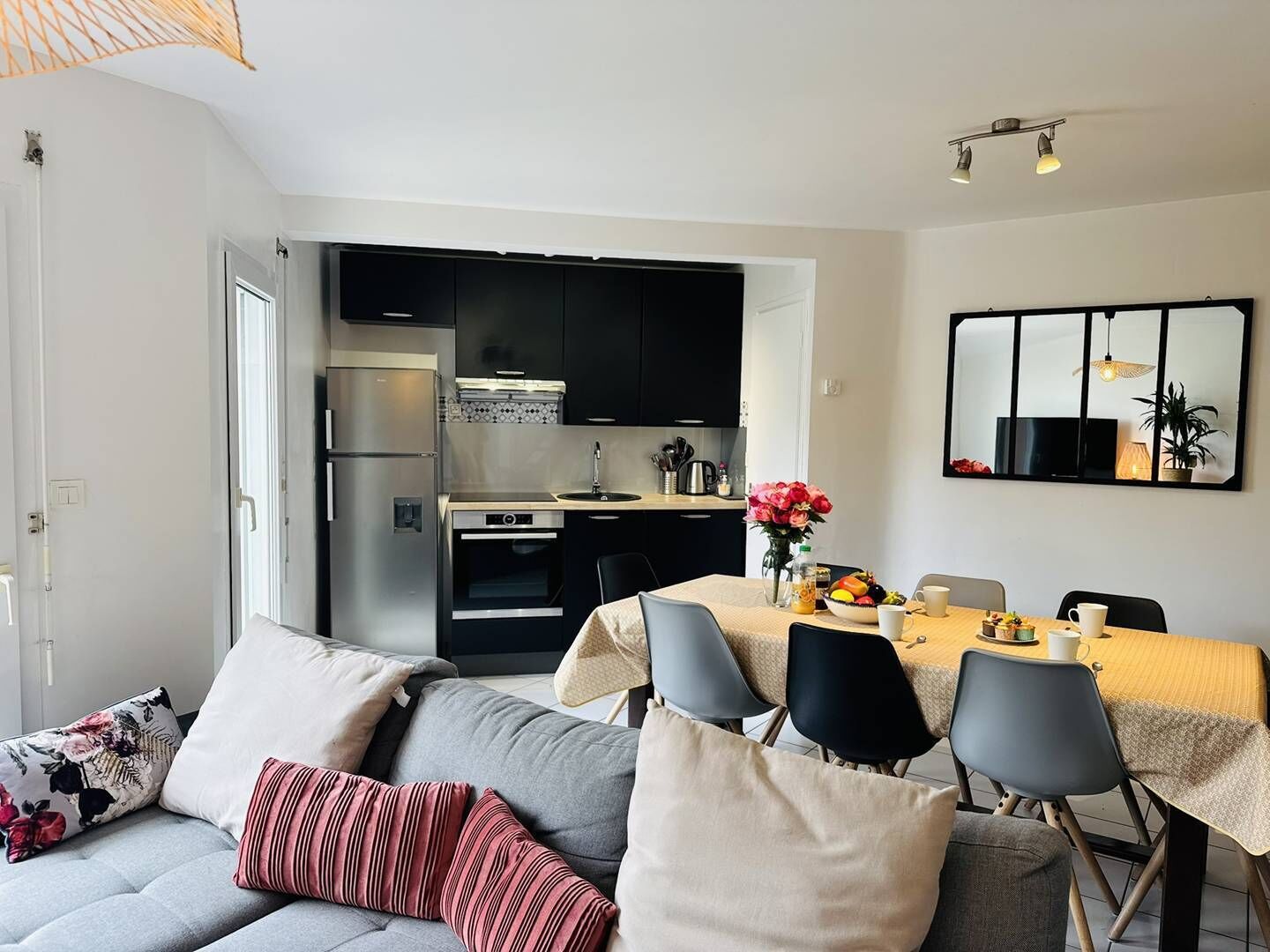 A compact living space with a kitchenette, dining area, and a sofa with cushions.