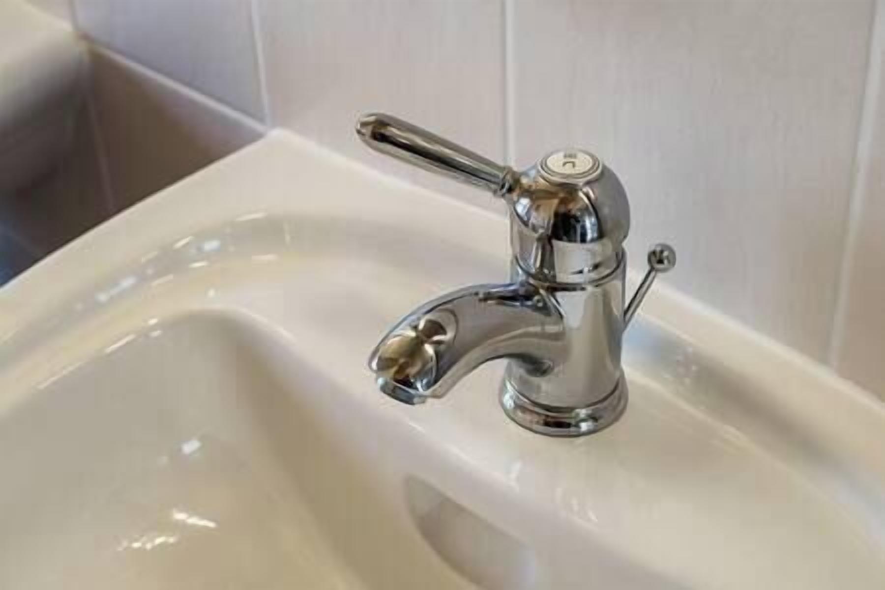 A modern bathroom sink with a chrome faucet and a single lever handle.
