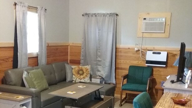 Een gezellige woonkamer met een bank, een salontafel, een eettafel met stoelen en een televisie.