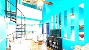 Una sala de estar con televisor, estantería y escalera.