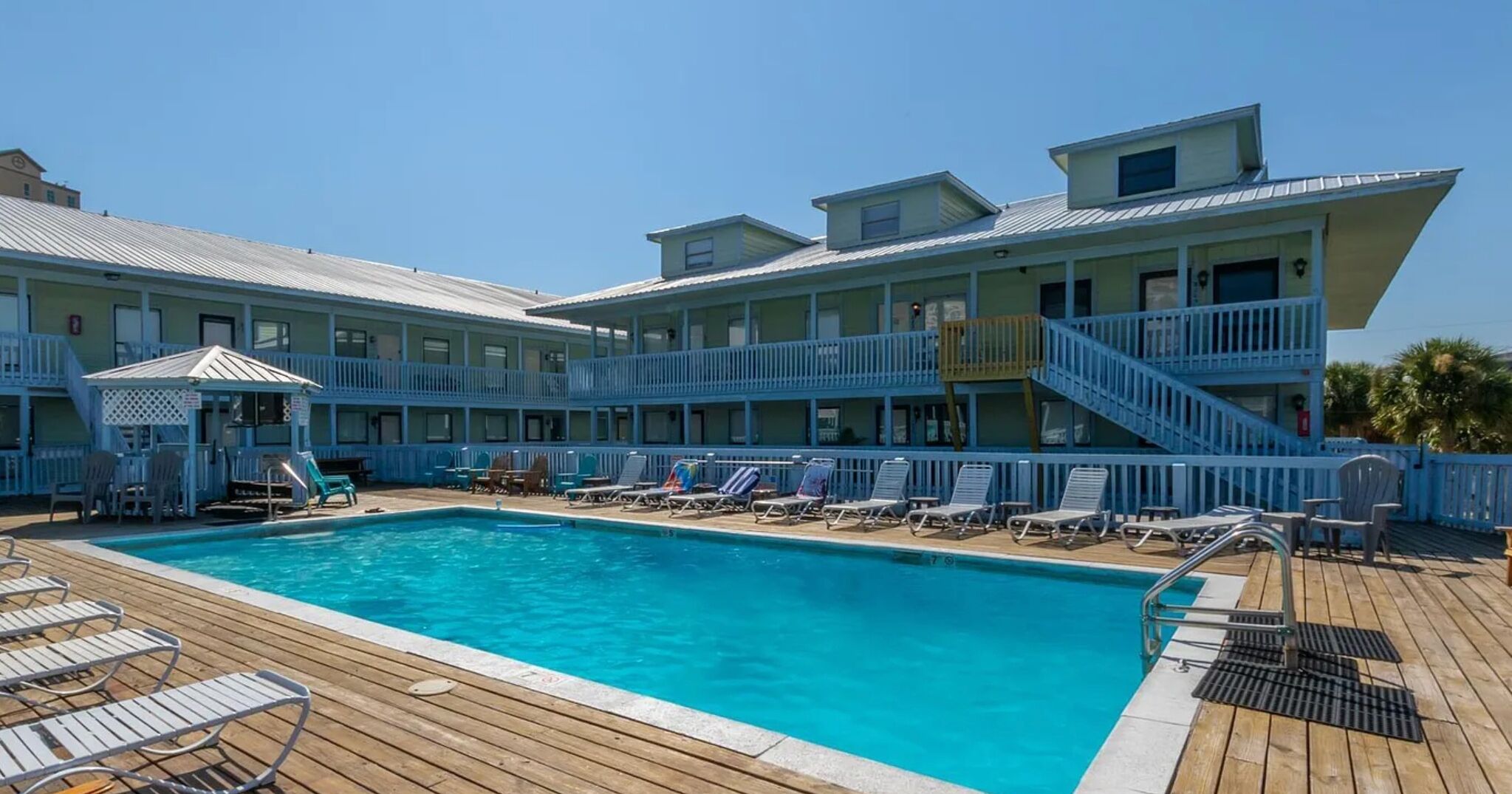 A pool area with lounge chairs and a small gazebo.