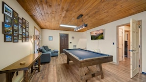 A room with a pool table, a sofa, and a wooden ceiling. - Spacious 6BR mountain retreat with hot tub, game room, and views. (Beech Mountain)