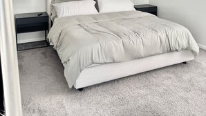 Ein modernes Schlafzimmer mit einem großen Bett, zwei Nachttischen und zwei Wandspiegeln.