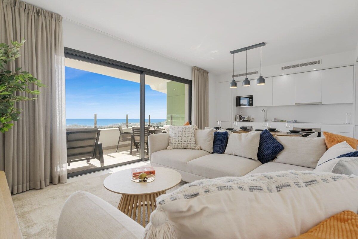 Un salon moderne avec un canapé, une table basse et une vue sur la mer.