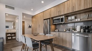 A modern kitchen with wooden cabinets, stainless steel appliances, and a dining area with a table and chairs. - Ski-Access  2 Queen Beds  Private Patio  Hot Tub (Park City)