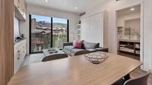 A modern hotel room with a balcony, a dining area, and a view of mountains. - Ski-Access  2 Queen Beds  Private Patio  Hot Tub (Park City)