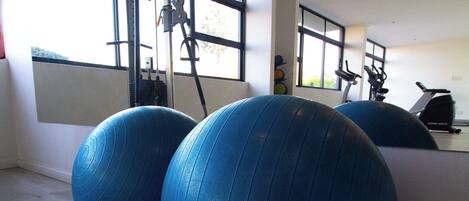 A gym with exercise balls, a treadmill, and a stationary bike.