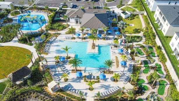 An aerial view of a resort with a central swimming pool, multiple lounge areas, and a golf course. - Champions Gate Gem – Pool, Spa, Near Parks (Davenport)