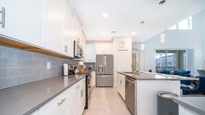 Une cuisine moderne avec des meubles blancs, des appareils en acier inoxydable et un bar pour prendre le petit-déjeuner.