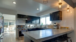A modern kitchen with dark cabinets, stainless steel appliances, and a large island with bar stools.