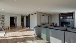 A spacious living room with a large sectional sofa, a fireplace, and a wooden floor.