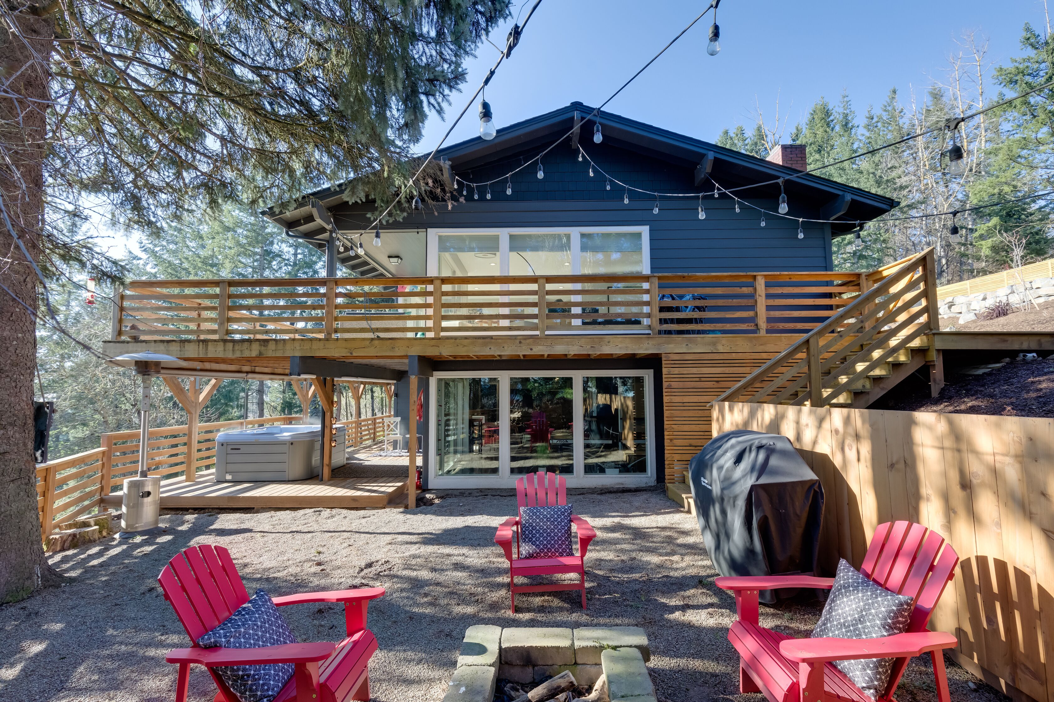 A two-story cabin with a deck, outdoor seating, and a fire pit.