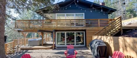 A two-story cabin with a deck, outdoor seating, and a fire pit.
