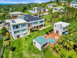 A modern residential area with multiple houses, a swimming pool, and solar panels.