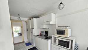 A compact kitchen with white cabinets, a black countertop, a microwave, a coffee maker, and a small oven. - CAP D'AGDE / Le Môle : Réf 0073 (CAP D'AGDE)