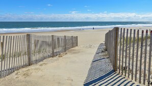 A sandy beach path leading to the ocean, bordered by wooden fences. - 2 Bedroom Ocean View Condo with Outdoor Pool! (Ocean City)